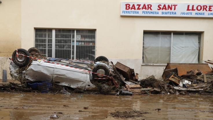 Ein Auto liegt nach einem schweren Unwetter auf Mallorca umgedreht auf einer Straße.