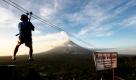 Ein Philippiner seilt sich an einem Seil, welches an einem Berg vor dem Vulkan Mayon abgebracht ist, ab. Der Vulkan Mayon in Legazpi hat in den letzten 24 Stunden fünf kleinere Ascheeruptionen gespeit, außerdem gab es mehrere Erdstöße. Zehntausende Menschen wurden in Sicherheit gebracht. Foto: dpa
