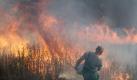 Mit Wasser aus einer großen Schüssel versucht ein Helfer, meterhohe Feuerwalzen zu löschen. Foto: dpa