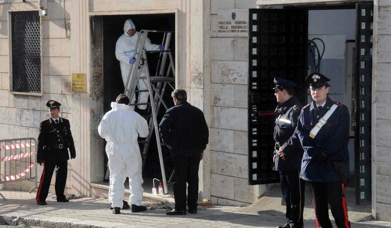 Carabinieri sichern im süditalienischen Reggio di Calabria den Eingang des Gerichtsgebäudes, während Tatortermittler Spuren sichern. Eine Bombenexplosion hinterließ schwere Schäden am Gebäude, niemand wurde verletzt.  Foto: ap