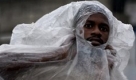 A man peers through a plastic sheet as he walks through the rain in Port-au-Prince, Tuesday, Sept. 22, 2009. (AP Photo/Ramon Espinosa) Foto: ap