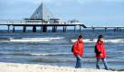 Touristen wandern vor der Seebrücke am Strand des Seebades Heringsdorf auf der Insel Usedom. Für die nächsten Tage haben die Meteorologen kühles und regnerisches Wetter vorausgesagt.  Foto: dpa