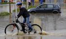 Ein Kind fährt am Freitag in Oesede bei Osnabrück ueber einen überfluteten Parkplatz auf dem noch ein Auto im Wasser steht. Starker Regen hatte den kleinen Fluss Düte über die Ufer treten lassen und die angrenzenden Gebiete unter Wasser gesetzt.  Foto: ddp
