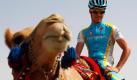Der Radsportler Simon Clarke vom australischen Team Astana lässt sich auf dem Rücken eines Kamels durch die Wüste tragen, bevor er bei der zweiten Etappe der Tour von Katar wieder in die Pedalen treten muss. Am Freitag endet der Wettbewerb nach fünf Etappen. Foto: dpa