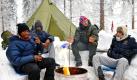 Die Sportstudenten Uche (von links nach rechts), Mauro, Martin und Ibrahim haben es sich vor ihren Zelten so gemütlich gemacht, wie es bei den niedrigen Temperaturen am Rande der Nordischen Ski-Weltmeisterschaft in Oslo geht. Foto: dpa