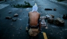 A supporter of Honduras's ousted President Manuel Zelaya sits on a rock in a road block during a protest in Tegucigalpa, Tuesday, Sept. 22, 2009. Baton-wielding soldiers used tear gas and water cannons to chase away thousands who demonstrated outside the Brazilian Embassy on Tuesday, leaving deposed President Manuel Zelaya and 70 friends and relatives trapped inside without water, electricity or phones. (AP Photo/Rodrigo Abd) Foto: ap