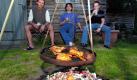 Sylvio Maltha, Mike Nilles und Klaus Leidinger (v.l.) schwenken am Sonntag (19.05.02) im Garten ihres Saarbruecker Hauses verschiedenartige Fleischstuecke auf einem Grill ueber dem Feuer. 'Der liebe Gott lenkt - der Saarlaender schwenkt' ist fuer viele Saarlaender im Sommer das Motto. Waehrend man anderenorts einen unbeweglichen Grill zum Braten von Fleisch benutzt, ist es im Saarland Tradition, zu Schwenken: Der Grill haengt an Ketten ueber dem Feuer. Im Saarland schwoert man darauf, dass diese Art des Grillens dem Fleisch einen unvergleichlich guten Geschmack gibt. Foto: Iris Maurer/ ddp Foto: ddp