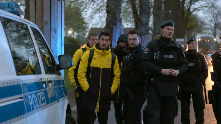 Spieler von Borussia Dortmund, darunter Sven Bender und Nuri Sahin, werden von Polizisten zum Hotel gebracht.