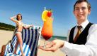 ILLUSTRATION - Der Barkeeper des Cliff-Hotels im Ostseebad Sellin auf der Insel Rügen, Rene Kraus, serviert Virginie am Donnerstag (03.06.2010) einen Sommer-Cocktail mit dem Namen Cliff-Sunrise direkt an den Strandkorb. Das Hotel startet zum kommenden sommerlichen Wochenende für seine Gäste diesen besonderen Strandservice. Foto: Stefan Sauer dpa/lmv/lno +++(c) dpa - Bildfunk+++  Foto: dpa