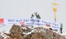 Mitglieder von Verdi halten nach ihrer Wanderung zum Gipfelkreuz der Zugspitze ein Banner mit der Aufschrift Voll auf der Höhe: Equal Pay in den Händen. Mit der Aktion protestierten die Gewerkschaftler aus Deutschland und Österreich gegen Leiharbeit. Foto: dpa
