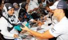 Bei einer Autogrammstunde in Kuala Lumpur reicht Formel-1-Pilot Michael Schumacher (McLaren Mercedes) einer Frau ein signiertes Basecap. Der Große Preis von Malaysia findet am kommenden Sonntag auf der Rennstrecke in Sepang nahe Kuala Lumpur statt. Foto: dpa