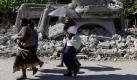 Einwohner des Ortes Leogane gehen an zerstörten Häusern vorbei. Foto: dpa