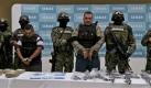 Navy members escort Martin Omar Estrada Luna, center, alias El Kilo, and alleged members of his gang in front of seized weapons and packages containing narcotics during a presentation to the press in Mexico City, Sunday, April 17, 2011. The Mexican Navy said Saturday it had captured Estrada Luna, the presumed leader of the San Fernando cell of the Zetas drug gang, suspected in the case of the mass graves found in Tamaulipas, as well as the migrant massacre last August in the violent border state across from Texas.  (AP Photo/Marco Ugarte) Foto: dapd