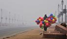 Ein Luftballonverkäufer in Neu Delhi bringt ein wenig Farbe in den vom Nebel dominierten Tag. Foto: ap