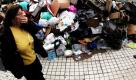 Ein Frau hält sich die Nase zu, als sie in Athen an einem Müllberg vorbeiläuft. Der Streik der Müllabfuhr ist nach ungefähr anderthalb Wochen beendet. Foto: dpa