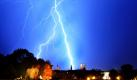 Ein gleißend heller Blitz schlägt in der Nacht in der Innenstadt von München ein. Im Vordergrund sitzt ein Pärchen, das sich das Wetterphänomen von einer Mauer des Bayerischen Landtags anschaut. Das heftige Gewitter zog in den späten Abendstunden über die bayerische Landeshauptstadt.
 Foto: dpa