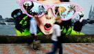 Passanten vor einem Graffiti in Köln. Die schräge Wandbemalung soll für den Kölner Zoo werben. Foto: dpa