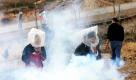 Palästinensische Demonstranten schützen sich mit Plastiktüten vor Tränengas, das vom israelischen Militär abgefeuert wird. Palästinenser haben in letzter Zeit häufiger gegen die im Westjordanland errichteten Grenzen demonstriert. 
 Foto: dpa