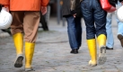 Passantinnen tragen in der Hafencity in Hamburg gelbe Gummistiefel und Schutzhelme in der Hand. Auf einer Fläche von 157 Hektar entsteht in der Hafencity ein innenstädtischer Raum mit einer Mischung von Arbeits- und Wohnnutzung, von Einzelhandel, Freizeit, Gastronomie und Kultur.
 Foto: dpa