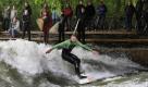 Ein Surfer reitet mit seinem Brett in der Welle des Eisbaches in München. Das Surfen im Eisbach ist eine Touristenattraktion, eigentlich aber verboten. Foto: ddp
