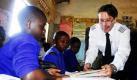 Der deutsche Pilot Uwe Thomas Carstensen (r.) erklärt den Schülern der St. Joseph's Grundschule in Wakiso in Uganda eine Aufgabe aus einem Buch. Mit seinem Co-Pilot Martin Grohganz ist er mit einer einmotorigen Maschine zu Besuch in zwanzig afrikanischen Ländern. Dort besuchen sie Projekte der deutschen Stiftung für die Weltbevölkerung, um in Deutschland eine Spendenkampagne zu initiieren. Foto: dapd