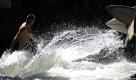 Ein Mann surft in München (Bayern) bei Temperaturen von fast 30 Grad auf der sogenannten Eisbachwelle im Englischen Garten. Nach dem sommerlichen Intermezzo am Wochenende wird es in der neuen Woche deutlich kühler. Foto: ddp