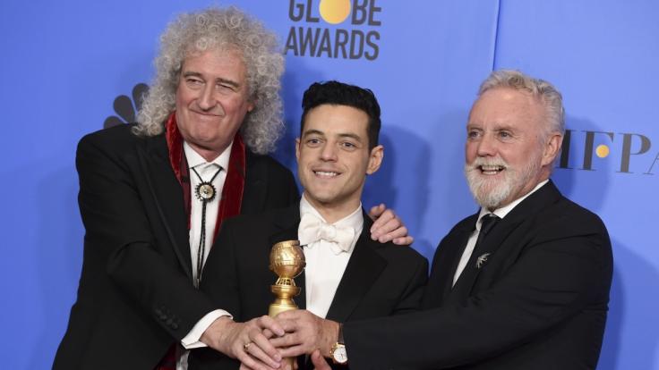 Brian May (l) und Roger Taylor (r) von der Band Queen freuen sich mit Rami Malek, der für