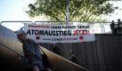 Aktionäre des Energiekonzerns E.ON AG gehen in Essen im Vorfeld der Hauptversammlung an einem Plakat von Umweltaktivisten mit der Aufschrift Dezentral statt katastrophal Atomausstieg Jetzt! vorbei. Der Energiekonzern E.ON AG stellt heute seine aktuellen Bilanzzahlen vor. Foto: dapd