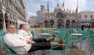 Auch diese Herren verzichten zwar nicht freiwillig auf die Arbeit, aber es scheint sie auch nicht zu bedrücken. Hochwasser auf dem Markusplatz von Venedig. Foto: dpa
