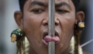 A devotees of the Jui Tui Chinese Shrine has his tongue pierced prior to a street procession at the Vegetarian Festival Saturday, Oct. 24, 2009, in Phuket, Thailand. The annual festival traces its origin back to the early 1800's when Chinese tin miners and others who had been stricken with disease recovered by adhering to a strict vegetarian diet. (AP Photo/David Longstreath) Foto: ap