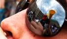 Eine Teilnehmerin eines Vuvuzela-Flashmobs vor dem Brandenburger Tor in Berlin bläst mit vollen Wangen in das Schwarz-rot-goldene Rohr und spiegelt sich dabei in der Sonnenbrille einer weiteren Teilnehmerin. Das sich an dem Flashmob nur wenige Vuvuzela-Bläser beteiligt haben und nicht so wie in Südafrika am vergangenen Mittwoch zehntausende Fans, störte die junge Dame nicht  sie hatte sichtlich Spaß.  Foto: dpa