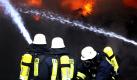 Feuerwehrleute versuchen die Flammen in der Lagerhalle eines Entsorgungsbetriebes in Freudenberg unter Kontrolle zu bringen. Löschtrupps sind mit einem Großaufgebot vor Ort. Wie es zu dem Brand kam, ist noch nicht geklärt. Foto: dpa