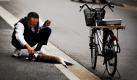 Ein Mann macht eine Pause, um eine kleine Katze in Tokio zu streicheln.  Foto: ap