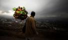 Ein afghanischer Mann mit künstlichen Blumen blickt auf die afghanische Hauptstadt Kabul. Foto: ap