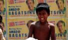 Philippinische Kinder spielen auf einem Müllberg an einer Straßenecke der Hauptstadt Manila. Im Hintergrund ist eine Mauer mit Wahlplakaten gepflastert  das Land steht kurz vor den Wahlen. Foto: dpa