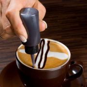Beginnen Sie entlang der Milchschaumlinien mit einer kleinen Flasche ein zweites Kreuz zu zeichnen. Beginnen Sie entlang der Milchschaumlinien mit einer kleinen Flasche ein zweites Kreuz zu zeichnen.