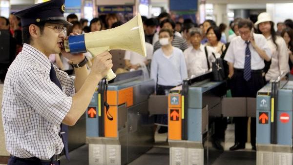 Achtung, Achtung, jetzt mal alle her hören: Die U-Bahn in Tokio ist voll! Da passt kein Mensche mehr rein! Wir wissen nicht genau, ob der Bahnbedienstete mit dem Megaphon tatsächlich den Füllstand der U-Bahn-Züge anprangert... (Foto)