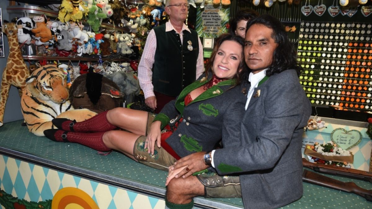 Christine Neubauer posiert mit ihrem Freund José Campos auf der Theke eines Schießstandes neben dem Käferzelt. (Foto)
