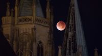 Der rötlich gefärbte Mond leuchtet am 28.09.2015 in Erfurt (Thüringen) hinter dem Dom.