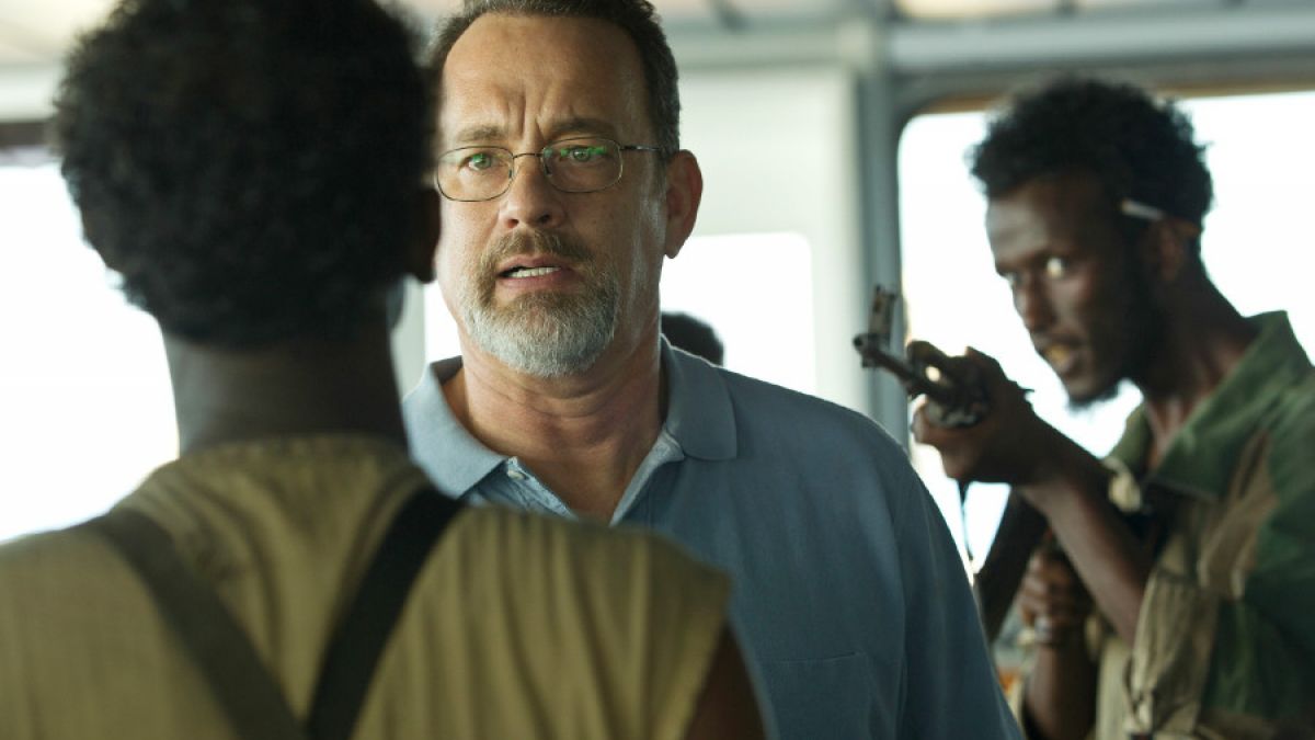 Captain Richard Phillips (Tom Hanks) wird von den Piraten Muse (Barkhad Abdi, l.) und Elmi (Mahat M. Ali, r.) bedroht. (Foto)