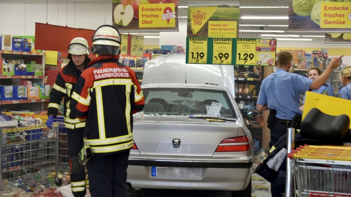Feuerwehrleute und Polizeibeamte stehen in einem Supermarkt neben einem Pkw, der zuvor in den Supermarkt gefahren war und dabei fünf Menschen verletzt hat. (Foto)