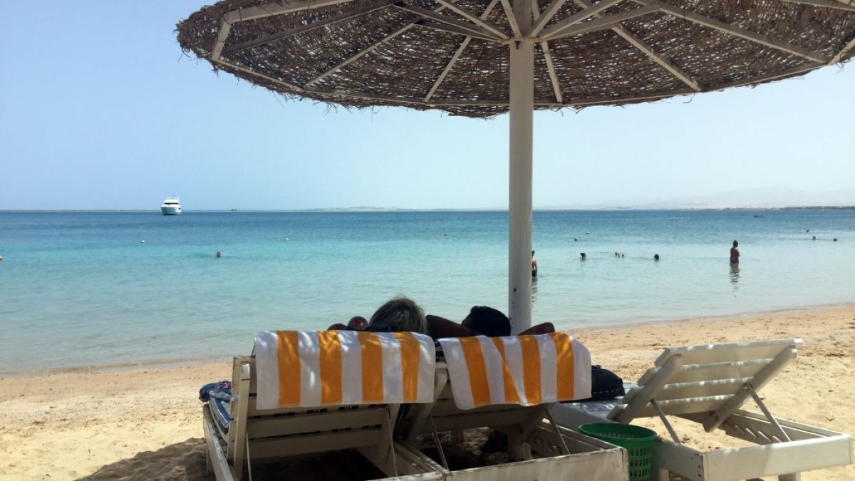 Eine Frau und ein Mann entspannen in Liegestühlen unter einem Sonnenschirm an einem öffentlichen Strand im ägyptischen Hurghada. Vor wenigen Tagen wurden in dem beliebten Urlaubsort zwei tote Hotelgäste aufgefunden. (Foto)