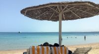Eine Frau und ein Mann entspannen in Liegestühlen unter einem Sonnenschirm an einem öffentlichen Strand im ägyptischen Hurghada. Vor wenigen Tagen wurden in dem beliebten Urlaubsort zwei tote Hotelgäste aufgefunden.