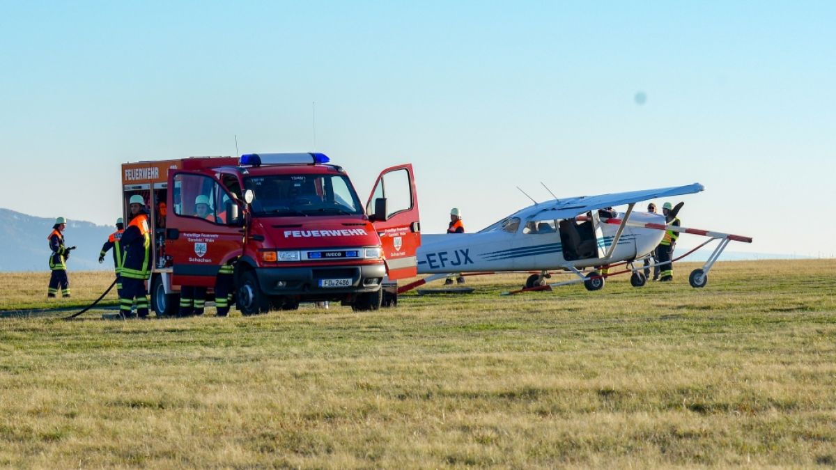 Feuerwehrleute stehen nach dem Flugunfall in Hessen neben dem verunglückten Sportflugzeug. (Foto)