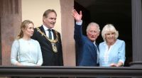 Der britische Thronfolger Prinz Charles und seine Ehefrau Camilla stehen mit Burkhard Jung, Bürgermeister von Leipzig und dessen Frau Ayleena auf dem Balkon des Rathauses und winken.