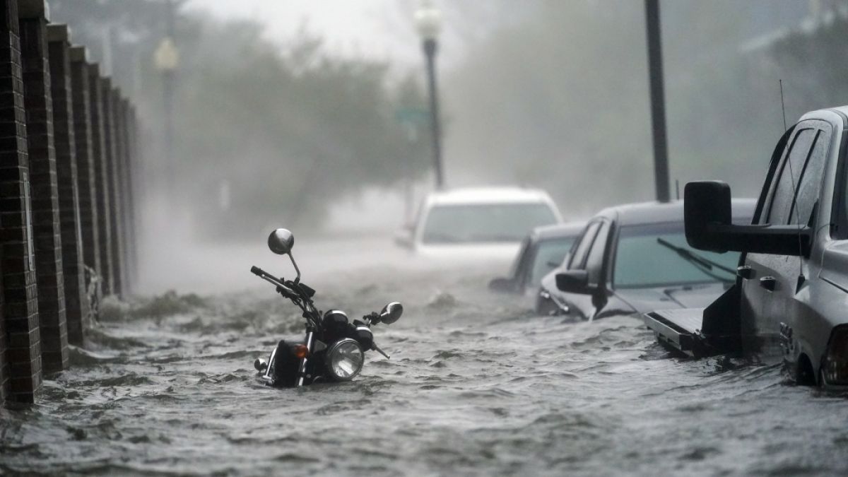 Fahrzeuge stehen auf einer überfluteten Straße. (Foto)
