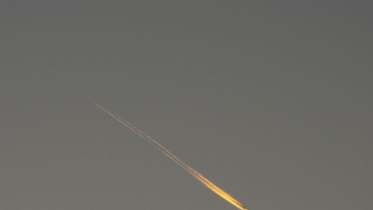 Ein Kondensstreifen wird von der untergehenden Abendsonne angestrahlt und sieht wie ein Feuerball aus.  (Foto)