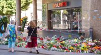 Trauerkerzen und Blumen liegen vor einem Kaufhaus in der Würzburger Innenstadt, in dem ein Mann Menschen mit einem Messer attackiert hatte.