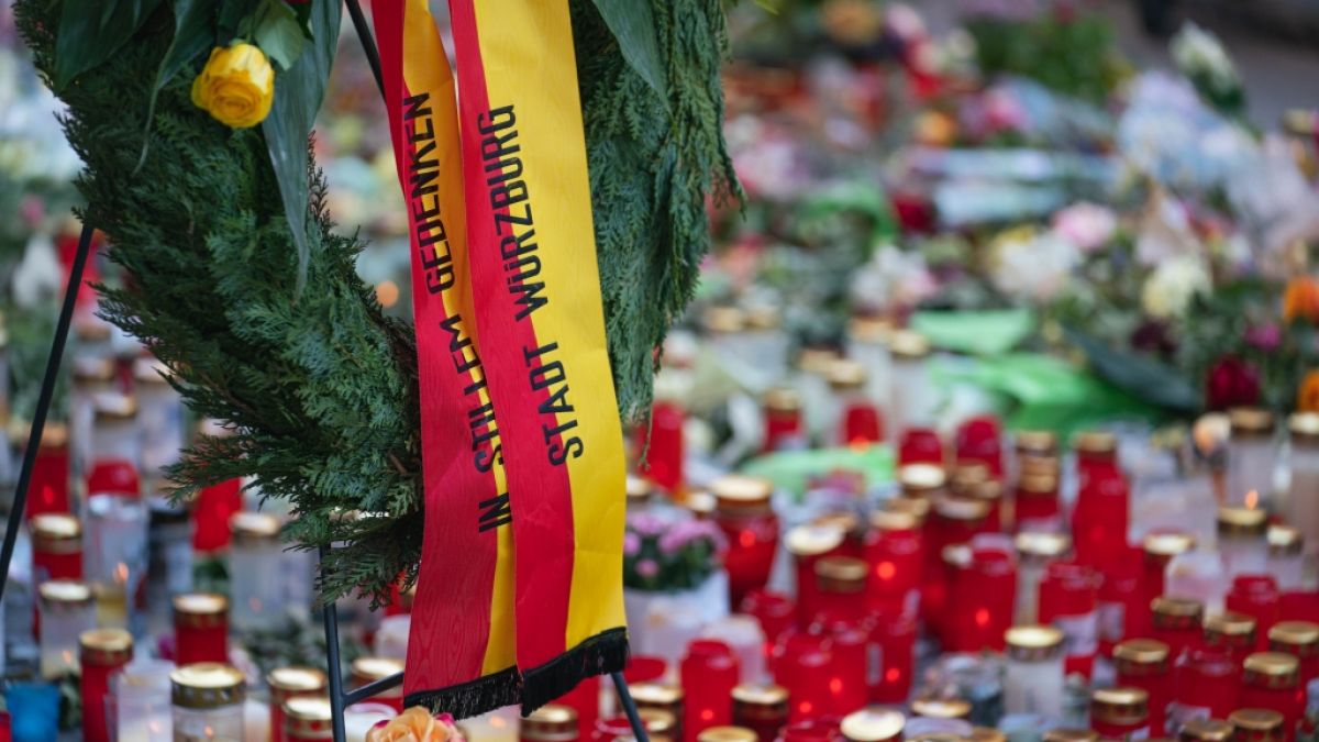 Trauerkerzen und Blumen, sowie ein Kranz der Stadt Würzburg, liegen vor einem Kaufhaus in der Innenstadt, in dem ein Mann Menschen mit einem Messer attackiert hatte. (Foto)