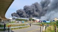 Eine dunkle Rauchwolke steigt über dem Chemiepark Leverkusen auf. Einsatzkräfte der Werkfeuerwehr sind im Einsatz.